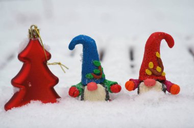 Beyaz karlı arka planda iki cüce. Oyuncak ağacın yanında..