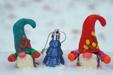 Beyaz karlı arka planda iki cüce. Oyuncak ağacın yanında..