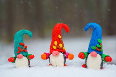 Beyaz karlı arka planda üç cüce figürü.