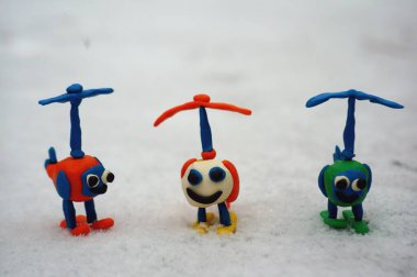 Beyaz karlı arka planda üç oyuncak renkli helikopter..