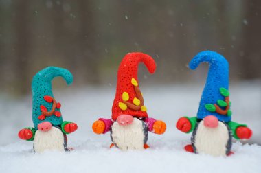 Beyaz karlı arka planda üç cüce figürü.