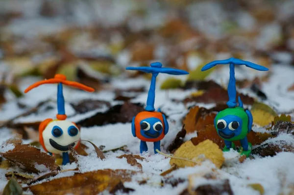 Karda sonbahar yapraklarının arka planında üç oyuncak renkli helikopter..