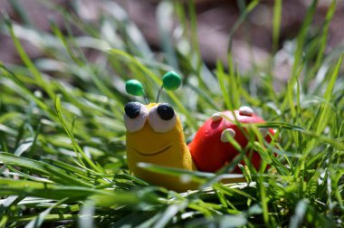 Yaban çiçeklerindeki plastikten yapılmış salyangoz heykelciği. Baharın sembolü..