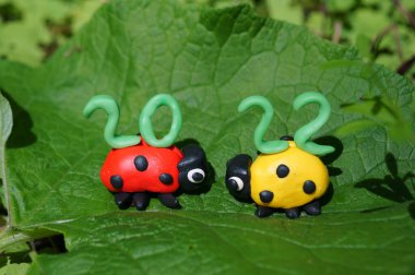 Plastikten yapılmış iki uğur böceği figürü. En üstte takvim tarihi 2022..