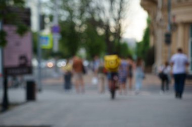 Arka plan bulanık. Bir grup insan eğlence parkında yürüyor..