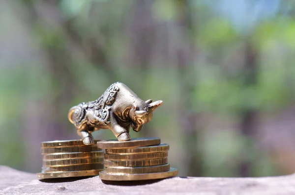 A metal bull figurine on a stack of coins. A financial symbol.