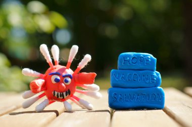 Plastikten yapılmış bir koronavirüsün yakın plan figürü. Yanındaki yazıt umut, aşı, kurtuluş..