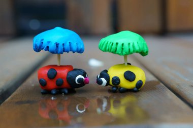 Plastikten yapılmış şemsiyeli iki uğur kuşu heykeli..