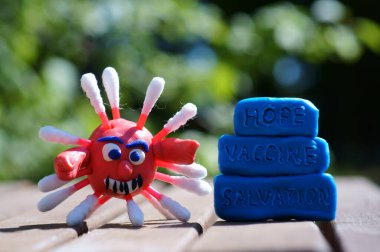 Plastikten yapılmış bir koronavirüsün yakın plan figürü. Yanındaki yazıt umut, aşı, kurtuluş..
