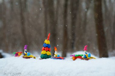 Plastikten yapılmış bir kar aracındaki Noel figürleri Noel ağacı ve hediyeler taşıyor. Eylem, karlı bir ormanda gerçekleşiyor..