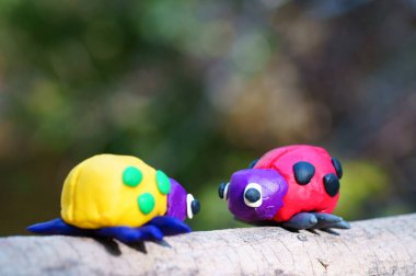 Renkli bir arka planda, ormanda plastikten yapılmış iki uğur böceği..