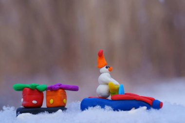 Karlı bir ormanda plastikten yapılmış bir kar aracındaki oyuncak kardan adam..