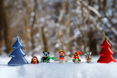 Kış ormanındaki peri masalı karakterlerinin figürleri. Yetenekli bir melek, cüce, havuçlu bir tavşan, bir panda, eşarplı bir penguen. Yakında oyuncak Noel ağaçları var..