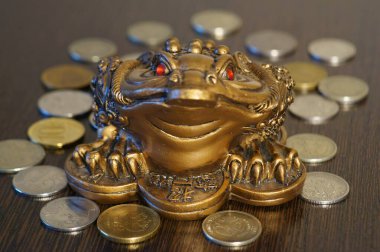 Masanın üzerinde bozuk paralar olan metal bir kurbağa. Bir finansal sembol.