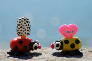 Mavi arka planda dondurmalı iki uğur böceği figürü. Tatlıya düşkünsün. Denizde bir tatil. Sıcak bir yaz günü.