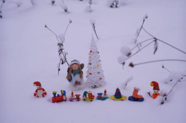 Plastikten yapılmış bir Noel treni ve karlı bir ormanda bir melek figürü..