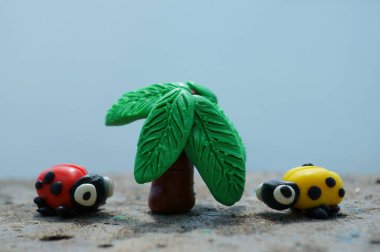 İki uğur böceği ve plastik ağaçtan yapılmış bir palmiye figürü. Yaz tatili.