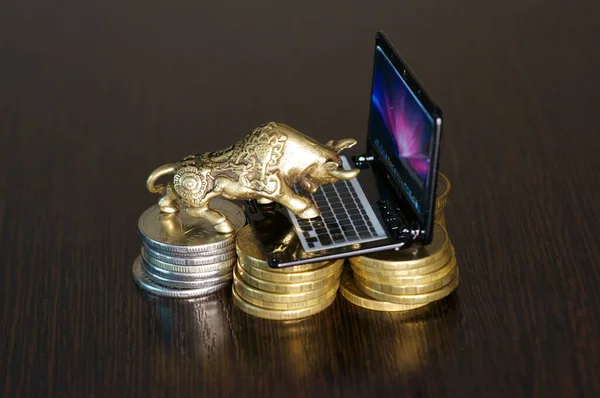 Metal bull and a toy laptop on the table close-up. Business concept.