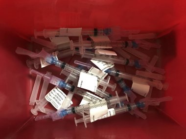 Indianapolis - Mart 2021: Coronavirus ve COVID-19 aşı şırınga ve şırınga. Harcanmış Moderna aşıları bir çöp kutusuna atılmış..
