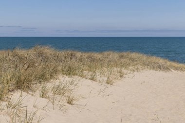 Michigan Gölü 'ne tepeden bakan kumlu kumulların güzel manzarası. Mavi su ve mavi gökyüzü. Uzaktaki bulutların soluk pembe bir tonu vardır..