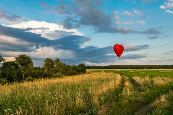 Globo de aire caliente rojo en forma de corazón en el cielo — Foto de Stock