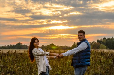 Gün batımında tutuşup bir çayırda genç Çift