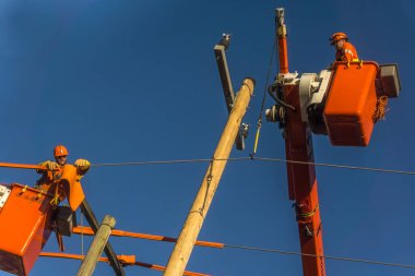 Toronto, Canada, October 2017 - Power linemen working on electric pole and cable for maintenance and repairs clipart