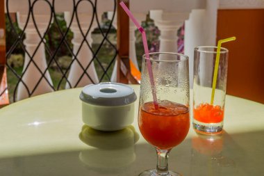 Bardaklar dolusu kokteyl, meyve suyu ve masada bir kül tablası.