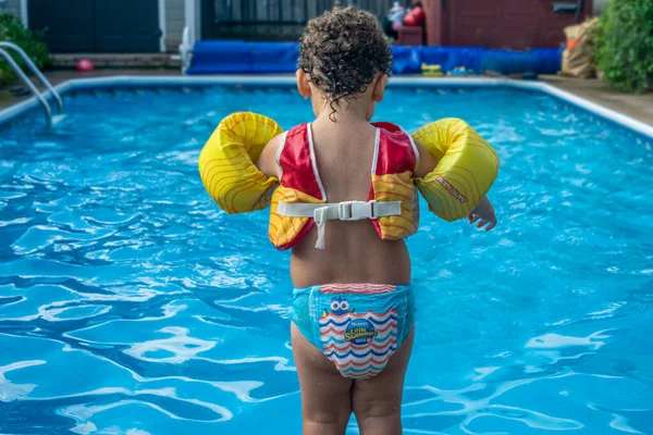 Kleine jongen in veiligheidskleding aan de rand van het zwembad en klaar om te springen Rechtenvrije Stockfoto's