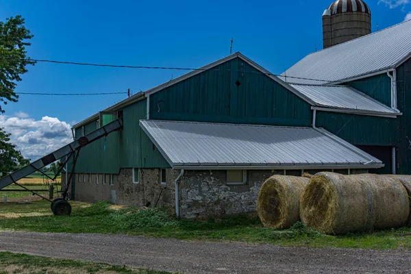 Green barn and silo with rolled stacks of hay — Stock Photo, Image