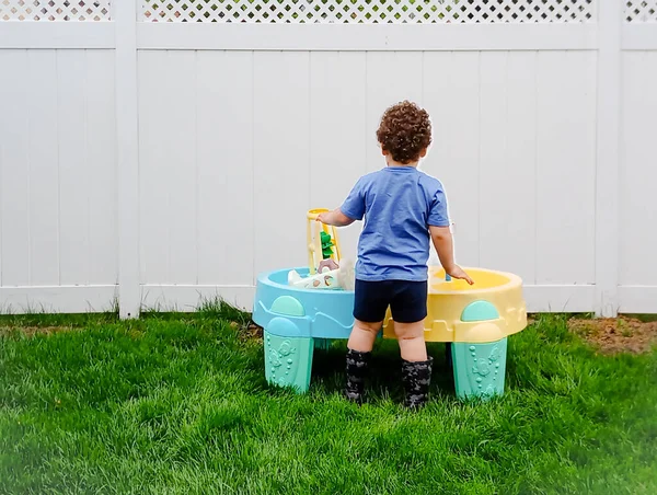 Little caucasian boy plays with a toy plastic tub in his backyard Stockfoto