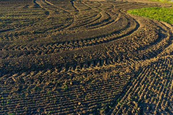 Tracks en groeven achtergelaten door trekker met bochtige patronen over een landbouwgrond — Stockfoto