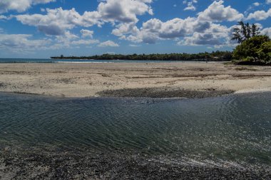 Tamarin, Mauritius - Sakin kıyı sahnesi sığ gel-git körfezi, kumlu sahil, ve sakin okyanus suyu açık mavi gökyüzü altında dağınık bulutlar