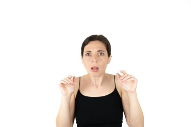 Genç ve güzel bir kadın beyaz arka planı düşünürken parmaklarıyla işaret ediyor.