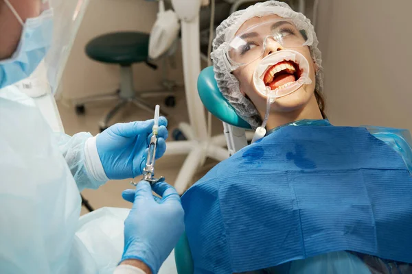 Dentist making local anesthesia shot before surgery. Patient visiting a dental office