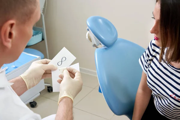 Man tandarts tonen zijn vrouwelijke patiënt een tandheelkundig implantaat — Stockfoto