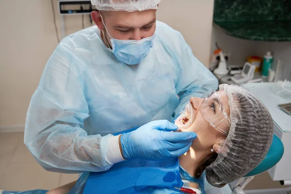 牙科医生对现代牙科诊所的病人使用橡胶扩展器 — 图库照片