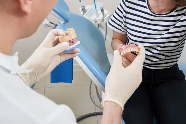 Man tandarts tonen zijn vrouwelijke patiënt een tandheelkundig implantaat — Stockfoto