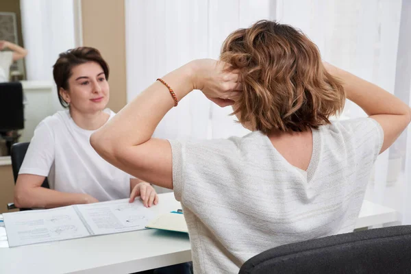 医者かマッサージの専門家は頭痛についての若い女性を相談する — ストック写真