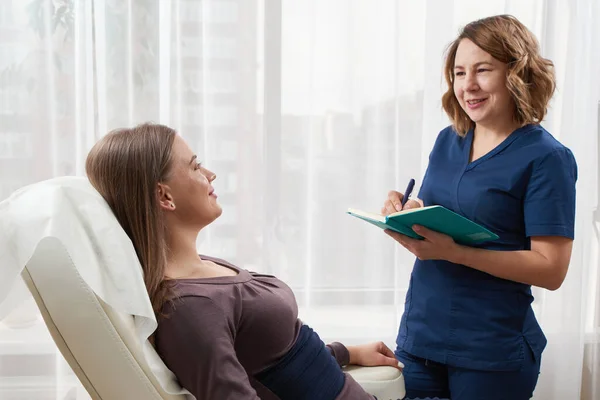 Médico está hablando con una paciente joven y tomando notas mientras está cerca — Foto de Stock