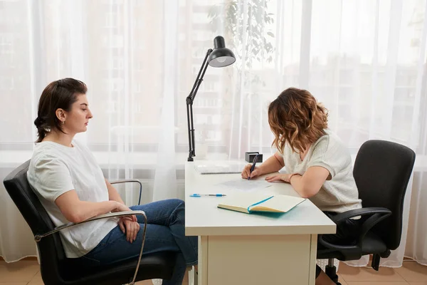 Young woman studying with private tutor at a table taking notes and reading