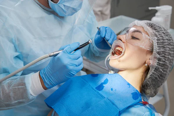 dentist drilling tooth to male patient in dental chair