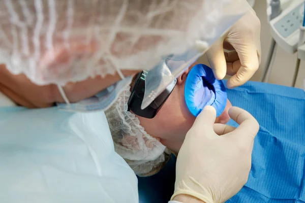 Tandarts doet een tandheelkundige behandeling bij een vrouwelijke patiënt. Tandarts onderzoekt een patiënt tanden in de moderne tandheelkunde kantoor — Stockfoto