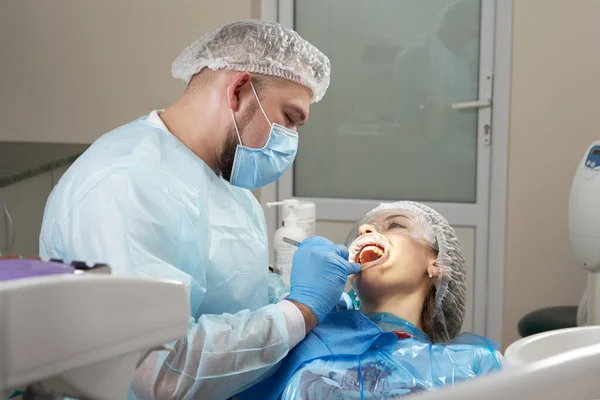 Zahnarzt bei einer zahnärztlichen Behandlung einer Patientin. Zahnarzt untersucht Zähne eines Patienten in moderner Zahnarztpraxis — Stockfoto