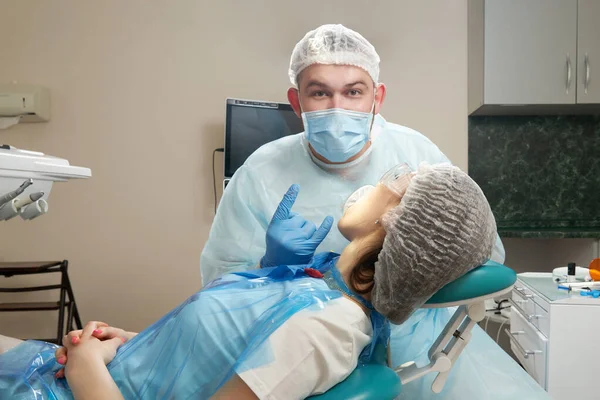 Tandläkare som gör en tandvård på en kvinnlig patient. Tandläkare undersöker en patient tänder i modern tandvård kontor — Stockfoto