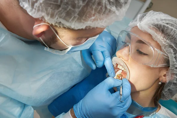 Dentist doing a dental treatment on a female patient. Dentist examining a patients teeth in modern dentistry office — Stock Photo, Image