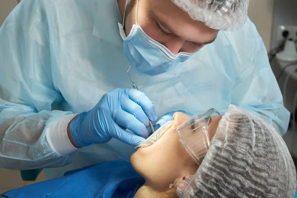 牙医对一位女病人进行牙科治疗.牙科医生在现代牙科诊所检查病人的牙齿 — 图库照片