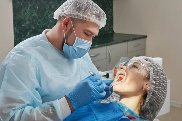 牙医对一位女病人进行牙科治疗.牙科医生在现代牙科诊所检查病人的牙齿 — 图库照片
