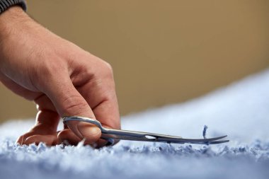 Halıdaki ipi makasla kesen elin yakın çekimi. Halı temizleme servisi
