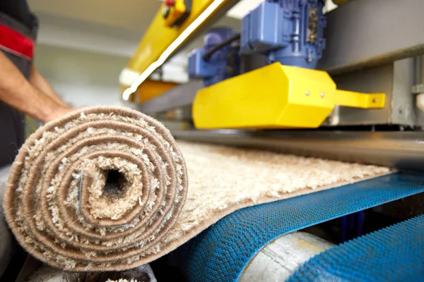 Pekerja laki-laki membersihkan karpet pada peralatan mesin cuci otomatis dan pengering di ruang cuci. layanan cuci profesional — Stok Foto